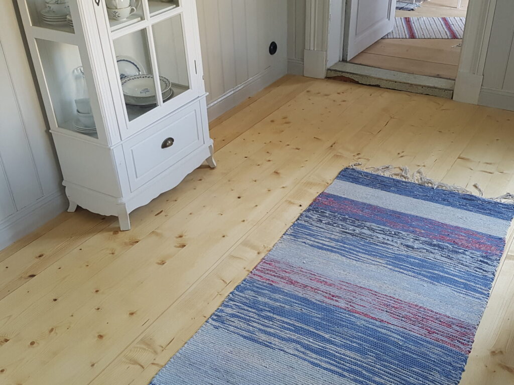Ett kilsågat grangolv i ett nytt kök med vackra trasmattor