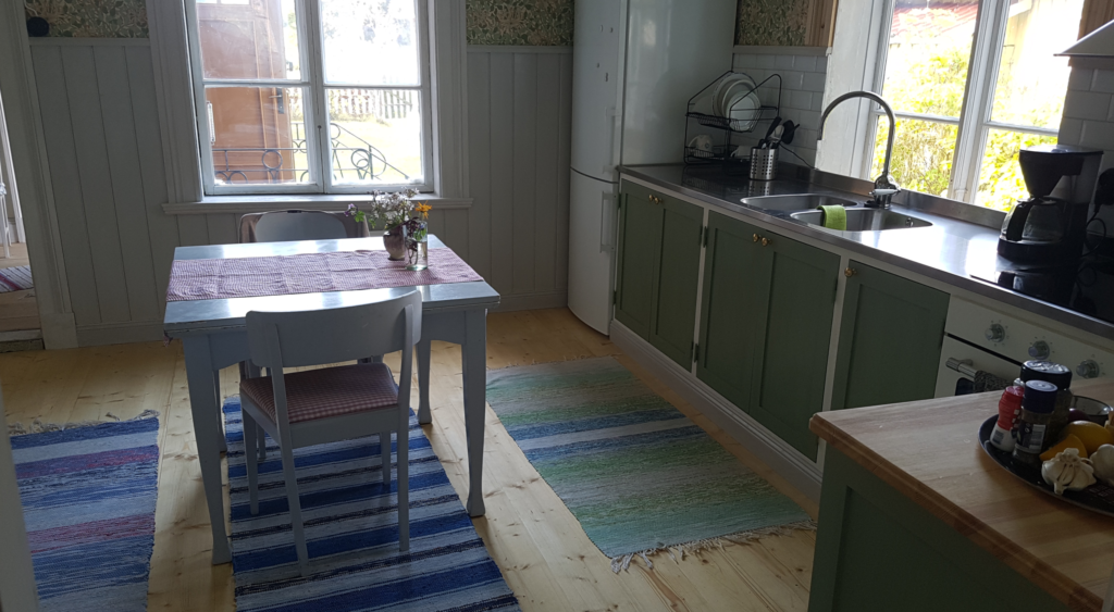 Nytillverkat kök i gammal stil med enkla spegelluckor. Platsbyggt och målat med linoljefärg.