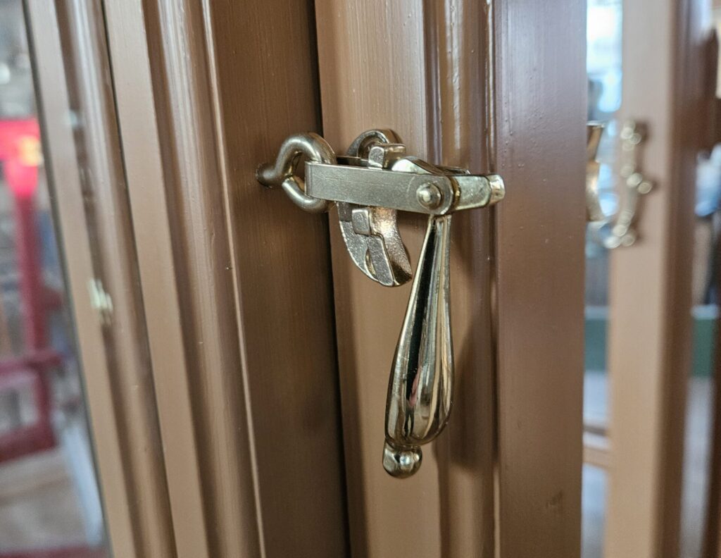 Detalj på kopplat fönster med droppformat stängningsbeslag i mässing.