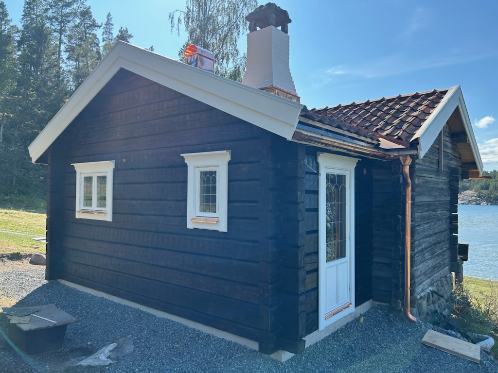 En över ett hundra år gammal timmerstuga har byggts ut på ett sätt som harmonierar med ursprunget. Blyspröjsade fönster och dörr är nytillverkade i gammal stil för att passa till huset.